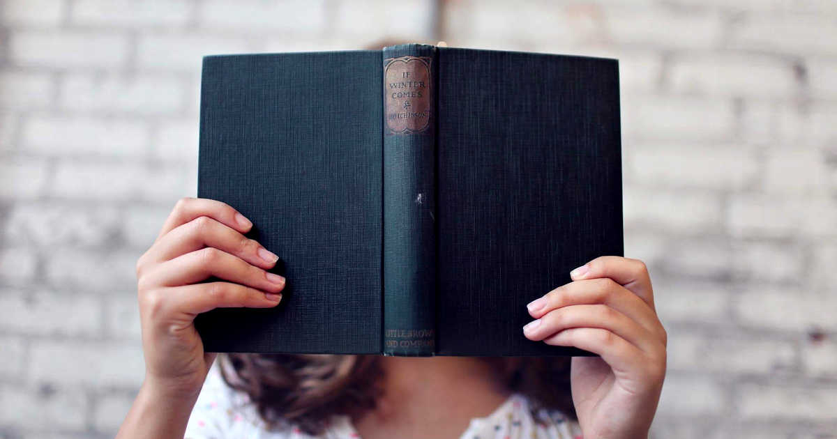 Una ragazza con il volto coperto da un libro